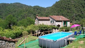 Una casa con piscina, rodeada de vegetación y colinas.