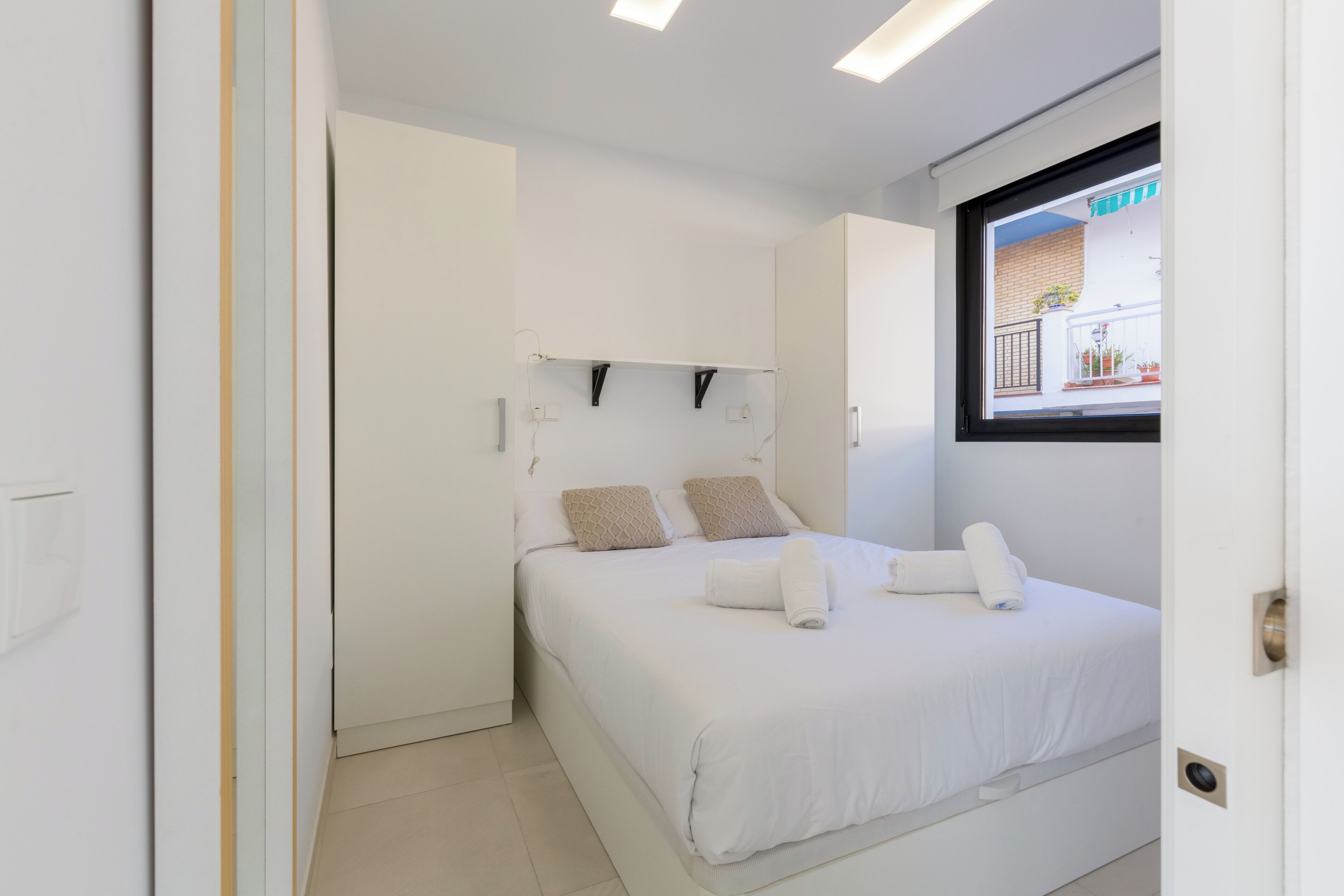 Camera da letto moderna con un letto, pareti bianche e una finestra con vista esterna.