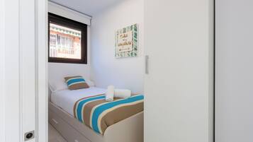 Une petite chambre à coucher, bien rangée, avec un lit, une fenêtre et une œuvre d’art murale inspirante.