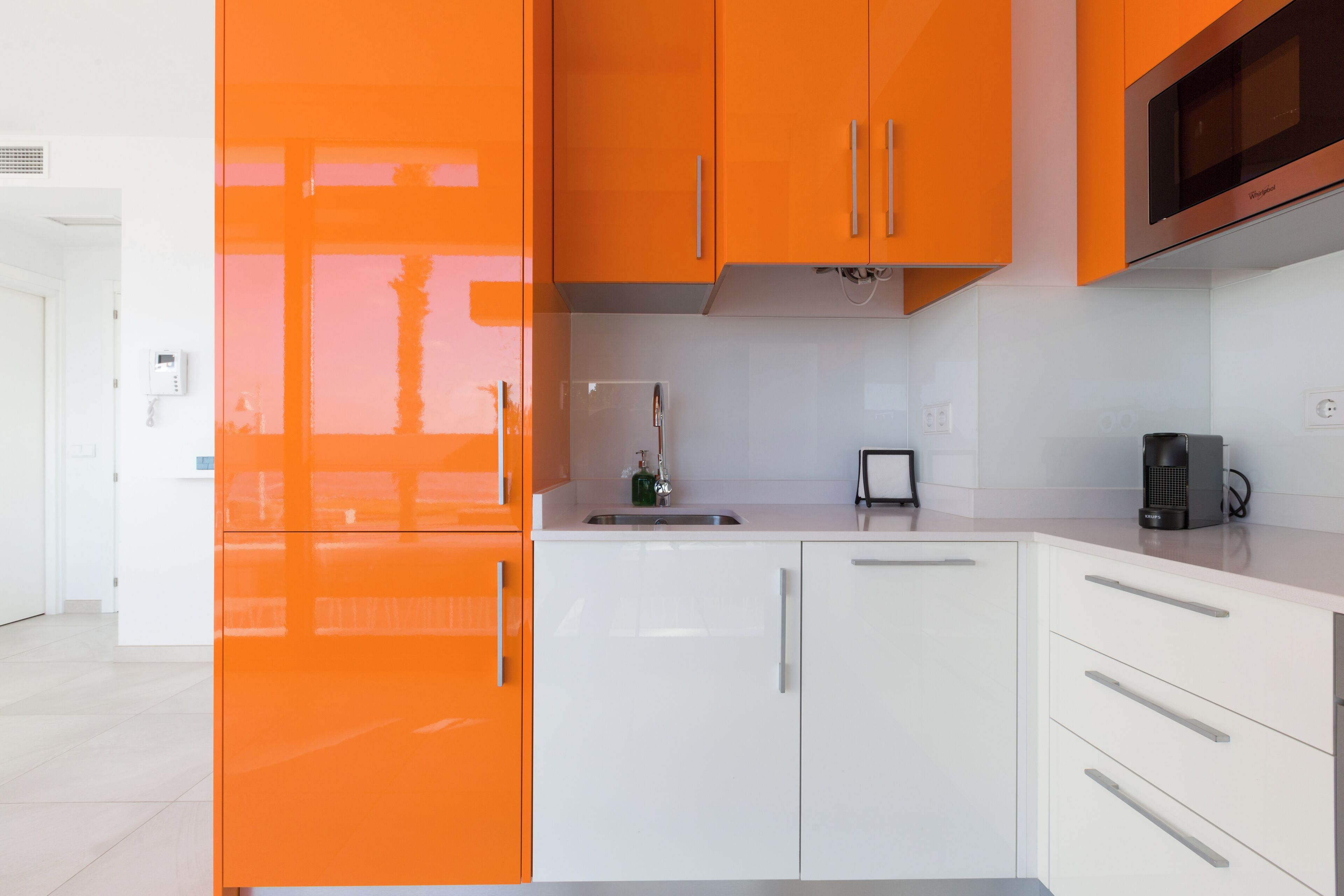 Een moderne keuken met oranje kastjes, een witte koelkast en een koffiezetapparaat.