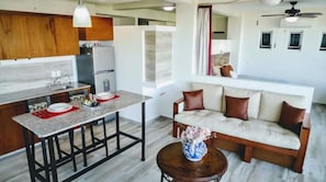 Eine moderne Küche mit einer zentralen Kochinsel, einem Essbereich mit einer Couch und einem Deckenventilator.