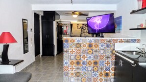 Una cocina moderna con salpicadero de azulejos, un televisor de pantalla plana y un ventilador de techo.