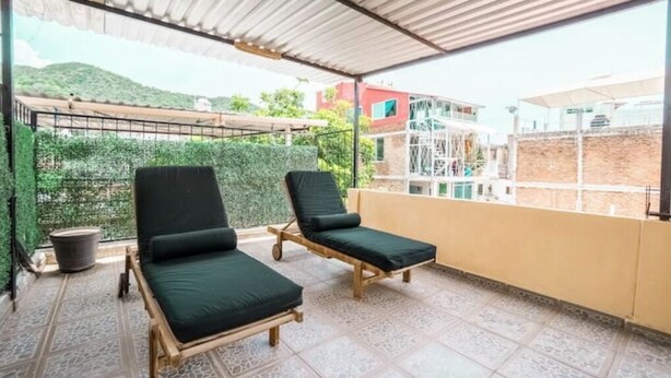 Un balcón cubierto con dos sillones de descanso y una planta en maceta.