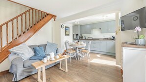 A cozy living room with a wooden staircase, a grey sofa, a wooden coffee table with tea set, and a kitchen in the background. - Escape to this exquisite holiday let in Tetford. (Tetford, near Horncastle)