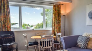 A cozy living room with a wooden table, two white chairs, a sofa, and a TV stand. - 2 bedroom accommodation in Beadnell, near Alnwick (Beadnell, near Alnwick)