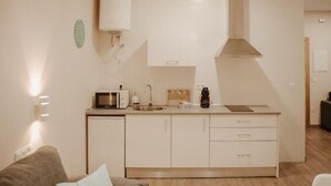 Een kleine keuken met een magnetron, broodrooster, spoelbak en kookplaat.