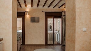 A hallway with a wooden ceiling, a television mounted on the wall, and a view of an outdoor balcony through a glass door. - Apartamento 1 dormitorio y 2 sofas cama Atlántica (Valdepeñas)