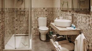 A modern bathroom with a glass-enclosed shower, a toilet, and a vanity with a sink and towel rack. - Apartamento Deluxe Mediterránea (Valdepeñas)