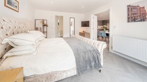 Quarto com uma cama grande, mesa de cabeceira, guarda-roupa e vista para a cozinha.
