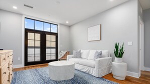 A modern living room with a white sofa, a round coffee table, and a blue patterned rug.