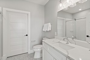 Une salle de bain moderne avec des toilettes blanches, un grand miroir et un meuble-lavabo.