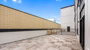 A covered outdoor area with a tiled floor and two wooden chairs.