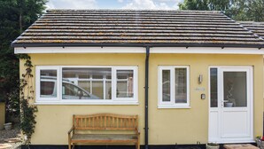 A yellow building with a tiled roof, a wooden bench, and a white door with a sign reading "GRACEY'S". - Gracies Cottage - UK44686 (Beamish)