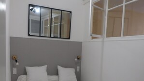A bedroom with a bed, a mirror, and a window. - T2 Rénové Hyper Centre, à 50 m de la Cathédrale (Rodez)
