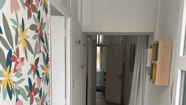 A hallway with a floral-patterned wall, wooden flooring, and a door leading to another room. - T2 Rénové Hyper Centre, à 50 m de la Cathédrale (Rodez)