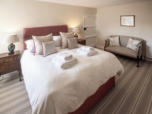 A hotel room with a large bed, a sofa, a nightstand with a lamp, and a door with a towel rack. - 2 bedroom accommodation in Ireby, near Bassenthwaite (Ireby, near Bassenthwaite)