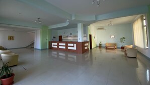 A spacious lobby with a reception desk, seating area, and potted plants. - Hostel Stefania (Costinesti)