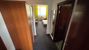 A hotel corridor with wooden doors, a bed, a chair, and a table. - Hostel Stefania (Costinesti)