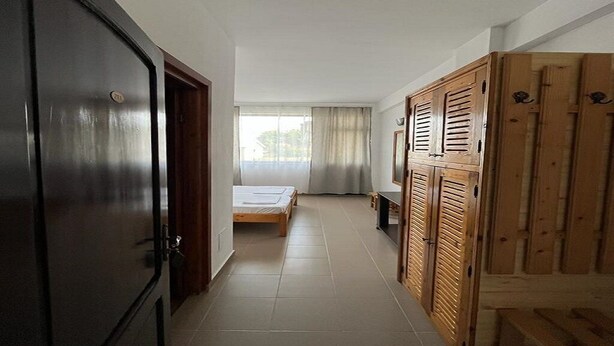 A hallway with a bed, wardrobe, and a door. - Hostel Stefania (Costinesti)