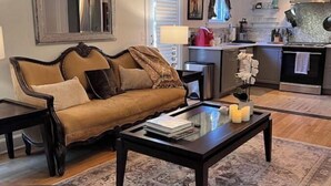 A living room with a sofa, coffee table, and a rug. There is a kitchen area with a stove and cabinets. - 4-room apartment in quiet, safe neighborhood (Nashville)
