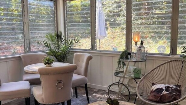 A sunroom with a round table, two chairs, a wicker chair, and a potted plant. - 4-room apartment in quiet, safe neighborhood (Nashville)