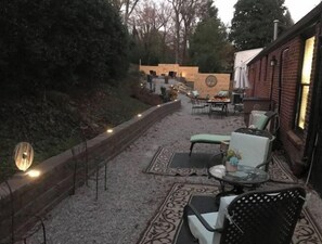 An outdoor patio area with seating arrangements, a decorative wall, and a brick building in the background.