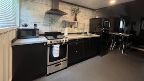 A modern kitchen with a gas stove, microwave, and black refrigerator. - Loft Where City Meets Country (Southgate)