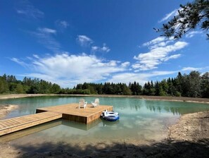 Un muelle de madera se adentra en un lago tranquilo con cielos despejados.