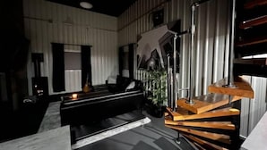 A modern living room with a black sofa, a coffee table, and a staircase with wooden steps. - Loft Where City Meets Country (Southgate)