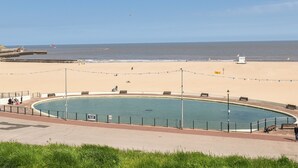 Una playa con piscina, bancos y una torre de socorristas.