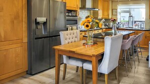 Eine moderne Küche mit Holzausstattung, Edelstahlgeräten und einem Essbereich mit Holztisch und Stühlen.