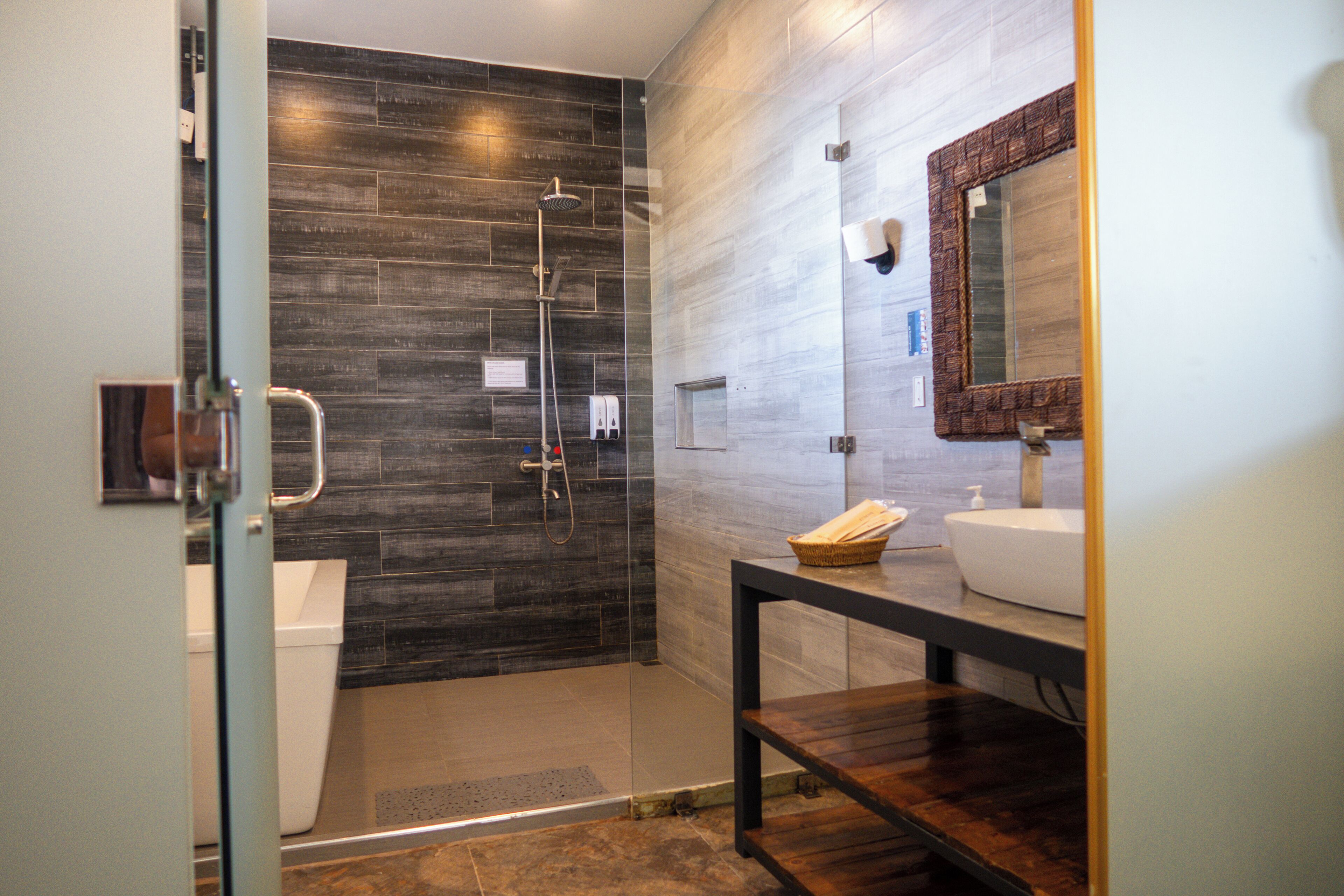 A modern bathroom with a glass shower enclosure, a white sink, and a wooden vanity.