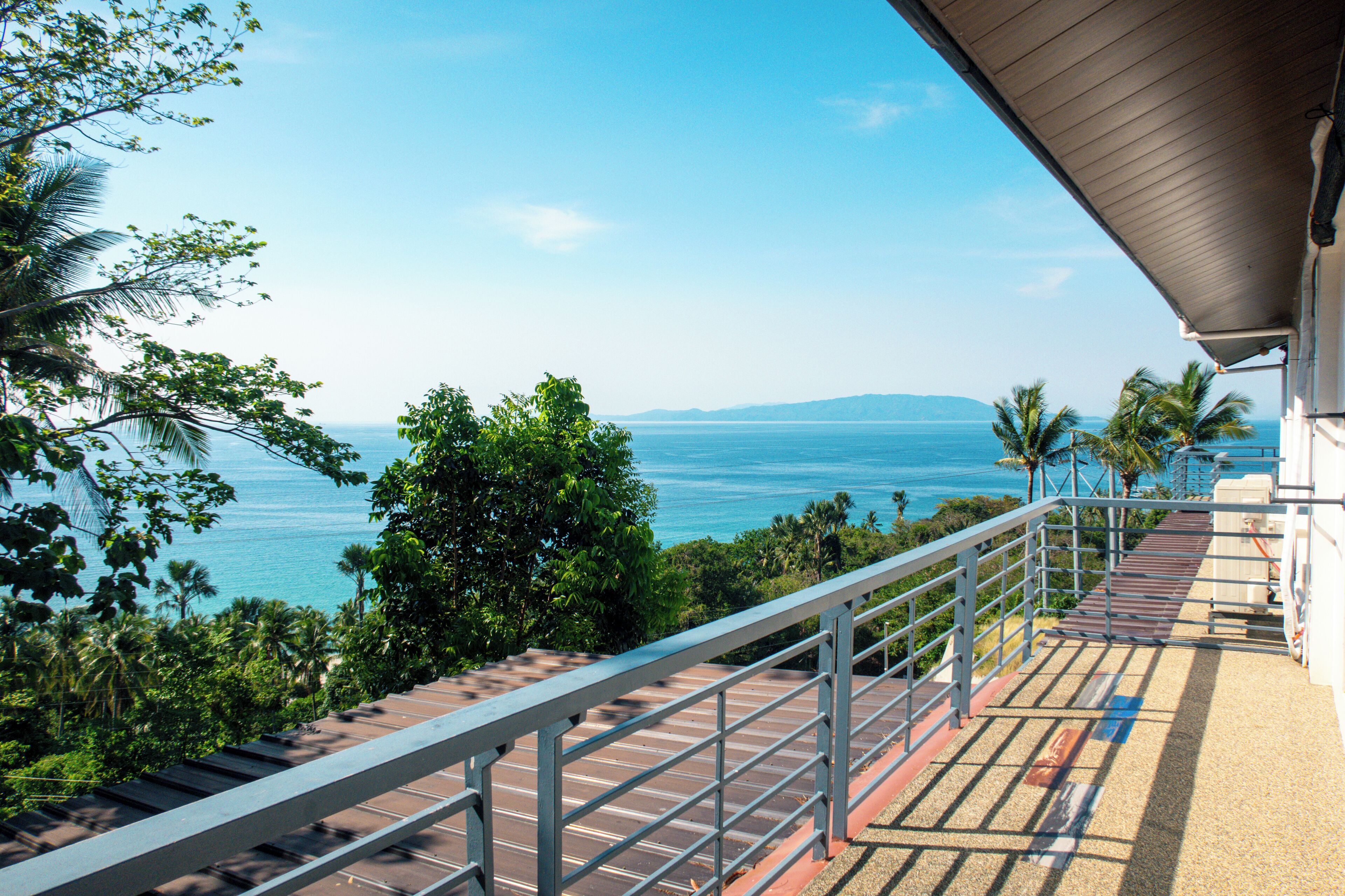 A balcony with a view of the ocean and palm trees.