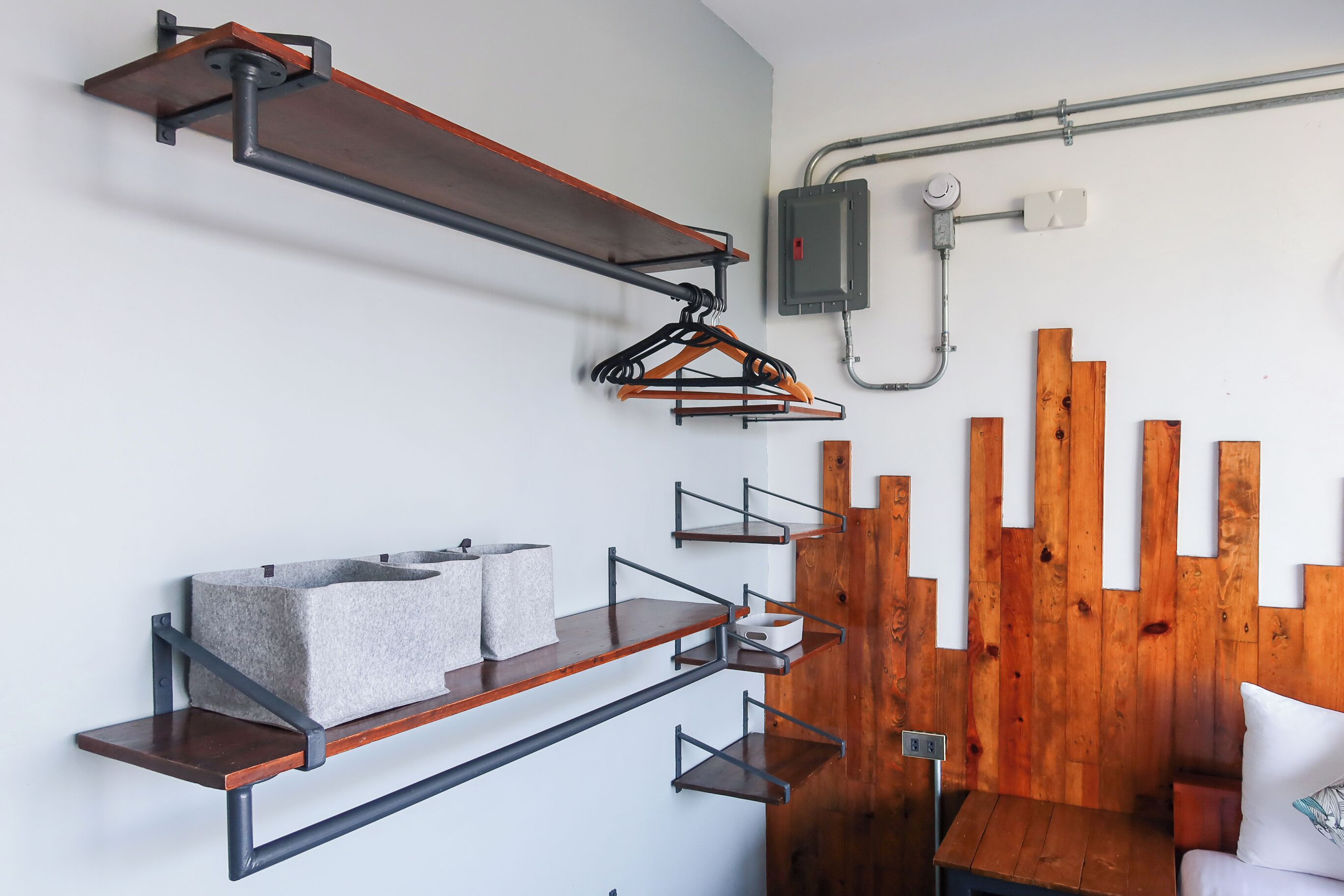 A modern room with wooden slats on the wall, metal shelves with towels, and a white bed.