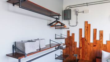 A modern room with wooden slats on the wall, metal shelves with towels, and a white bed.