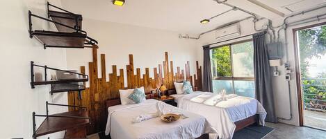 A modern hotel room with two beds, a wooden accent wall, and a large window offering a view of greenery.
