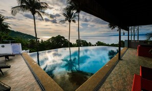 An infinity pool with a view of the ocean and palm trees. - AV Suites (Puerto Galera)
