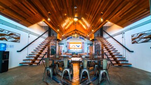 A spacious interior with a central staircase, wooden ceiling, and a dining area with metal chairs.