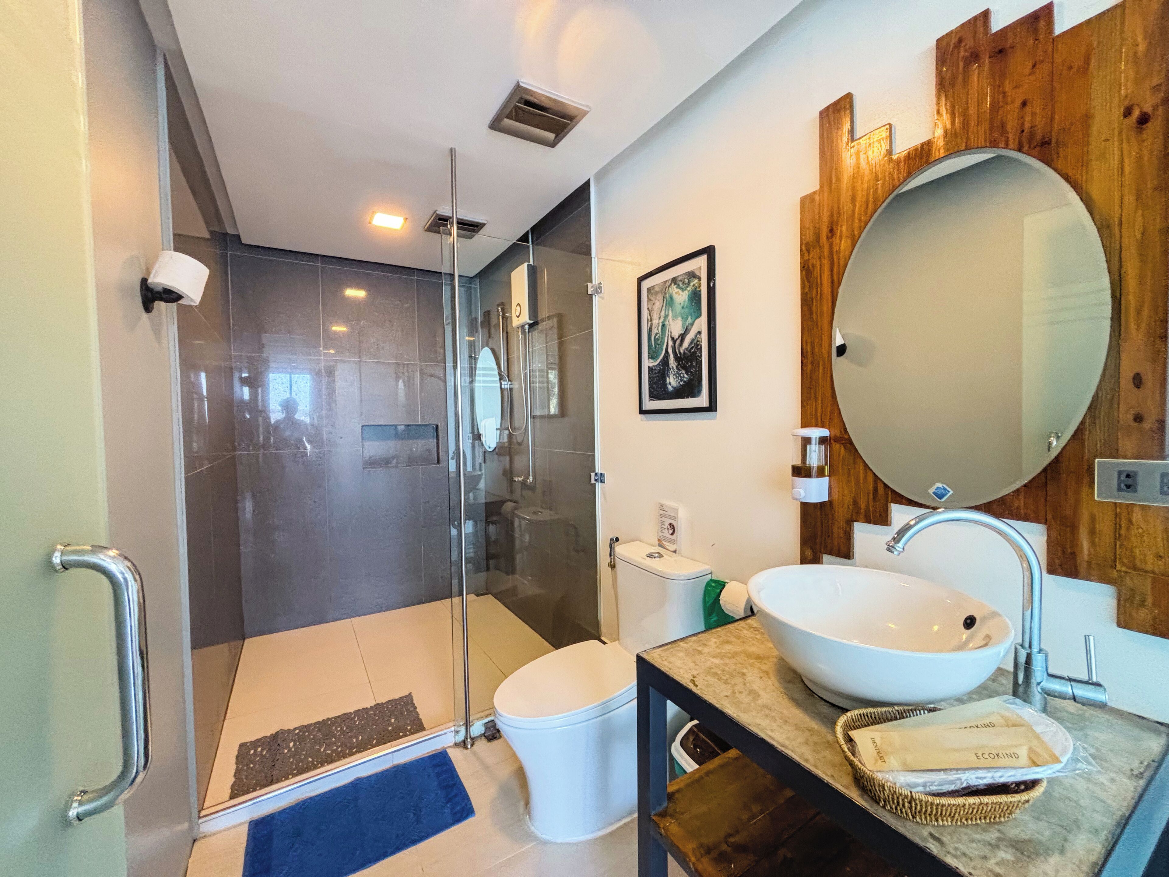 A modern bathroom with a glass shower enclosure, a white sink, and a wooden vanity.