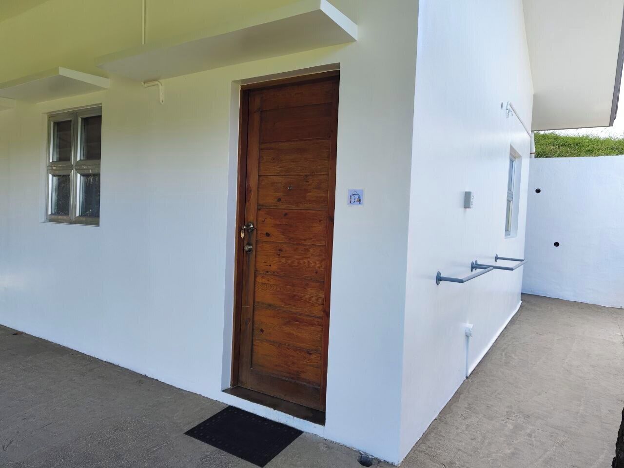 A modern building with a wooden door, a small window, and a metal handrail on the exterior wall.