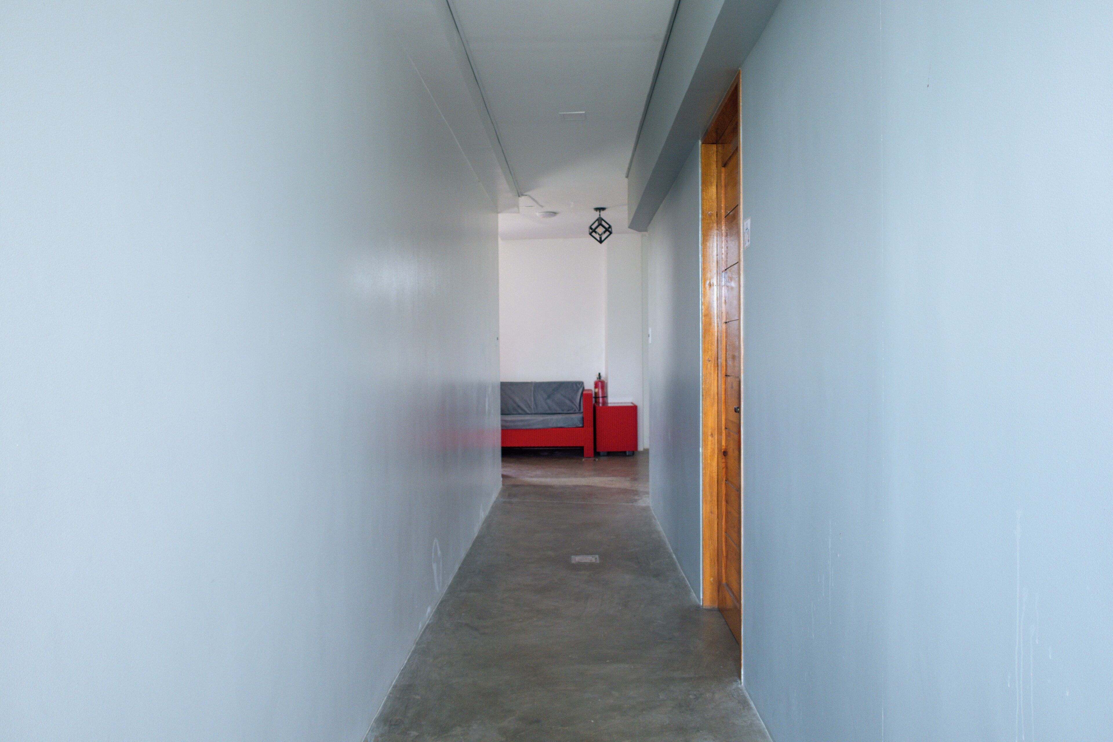 A narrow hallway with a bed and a nightstand in the distance.