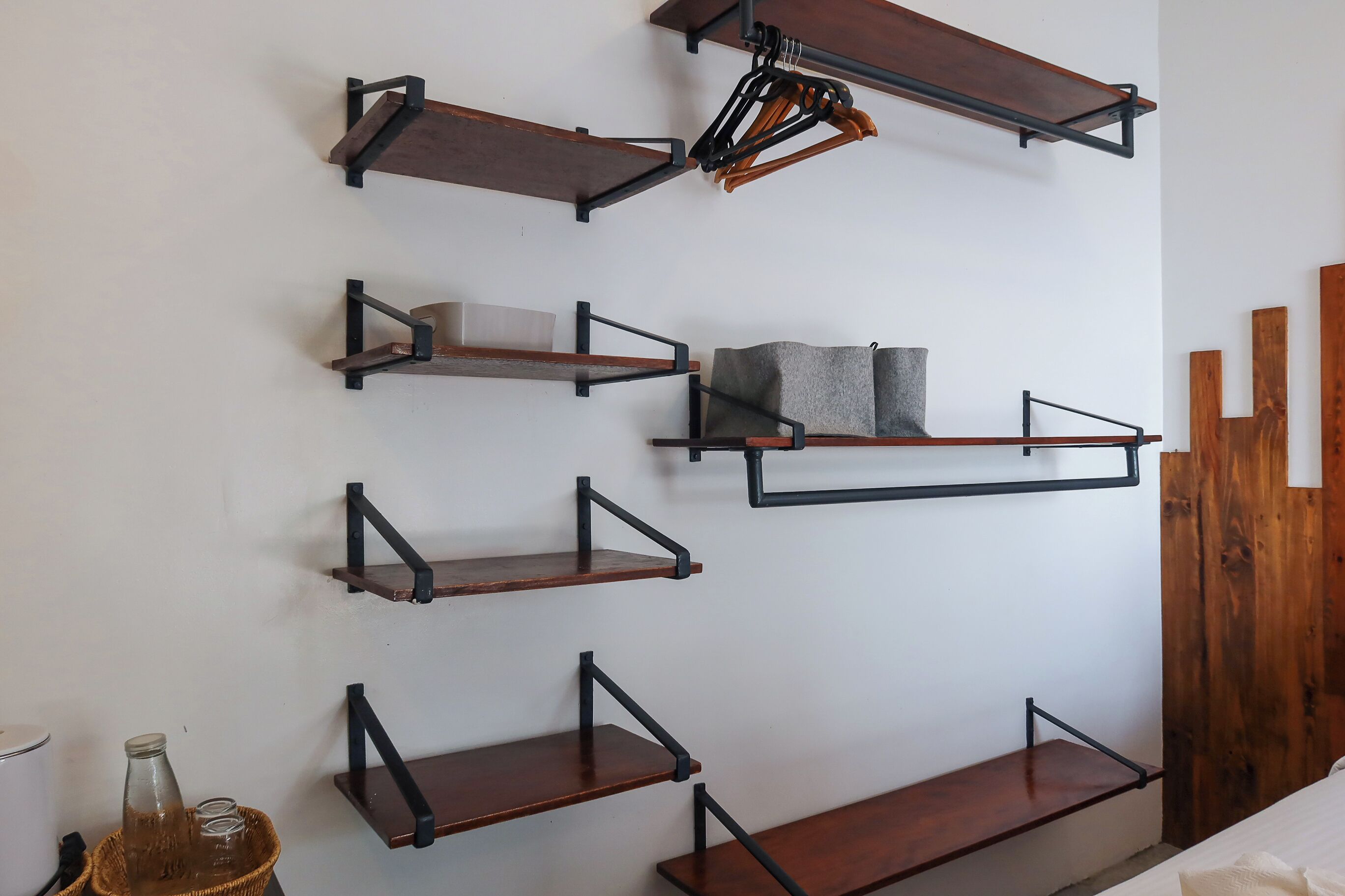 Una pared con varios estantes de madera de distintos tamaños y diseños, algunos con soportes metálicos.