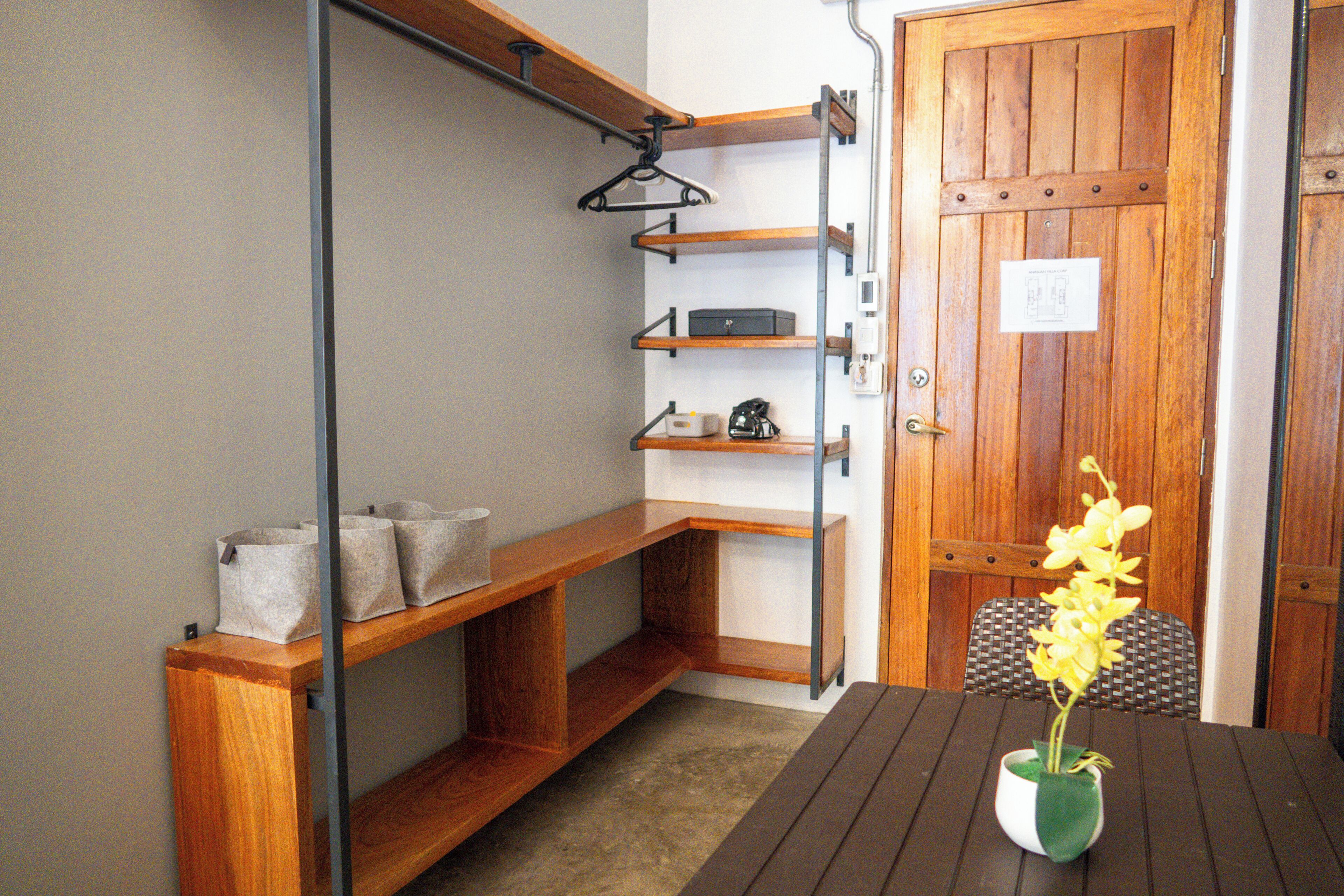 A compact room with a wooden bench, a small table with a vase of flowers, and a door with a wooden panel.