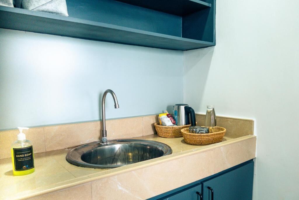 A kitchen sink with a faucet, a bottle of hand soap, and two wicker baskets containing kitchen items.