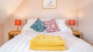 A neatly made bed with two pillows, a yellow throw, and two bedside lamps. - The Old Stable At Henley View (Draycott, near Cheddar)