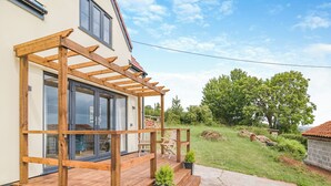 A wooden deck with a pergola, a glass door entrance, and a small outdoor seating area with chairs. - The Old Stable At Henley View (Draycott, near Cheddar)