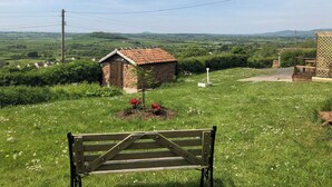 A rural landscape with a stone building, a wooden bench, and a clear view of the countryside. - The Old Stable At Henley View (Draycott, near Cheddar)