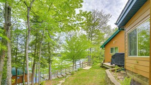 A cabin with a deck, a wooden staircase, and a view of the lake.