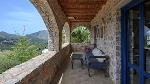 A stone-walled balcony with a wooden ceiling, a sofa, and a table. - Petritis,serene villa,pool,Near taverns,Crete,Greece (Lampini)