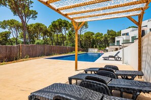 An outdoor pool area with a pergola, lounge chairs, and a view of a modern building. - AM-7 Modern house with shared pool (Llafranc)